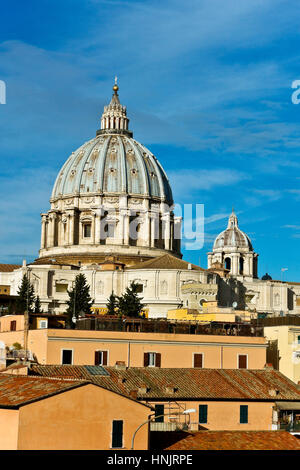 Unusual  view Saint Peter cathedral’s dome seen from the back, dominating the rooftops of adjacent buildings. Cupola Basilica San Pietro. Rome, Italy Stock Photo