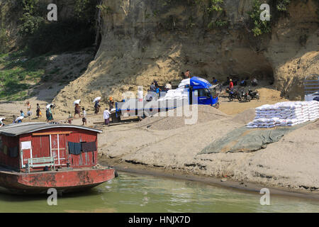 Men and women laborers are loading sacks from a cargo boat to a truck on the banks of the Irrawaddy River in Myanmar (Burma). Stock Photo