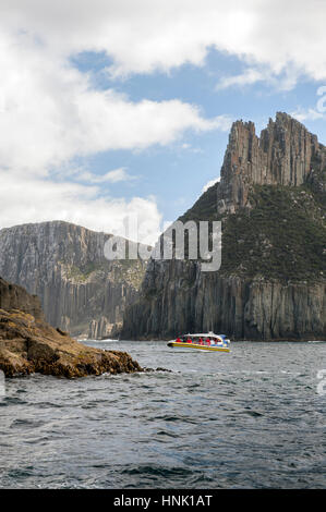 A cruise boat off the dramatic Cape Pillar on the Tasman Peninsula in Tasmania. Cape Pillar has the tallest dolerite cliffs in the Southern Hemisphere Stock Photo