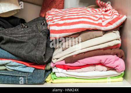 A stack of knitted warm woolen clothes in wardrobe close up Stock Photo