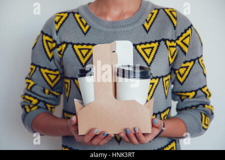 Woman holding a blank coffee cups in a carton on white background. Mock up. Stock Photo