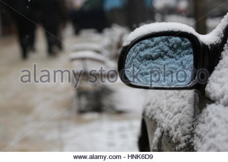 A car mirror and seats covered in snow after a heavy winter snowfall in downtown Budapest, Hungary Stock Photo