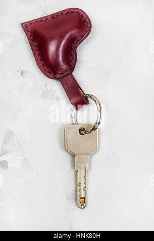 modern key with red leather heart shape keychain on concrete plate Stock Photo