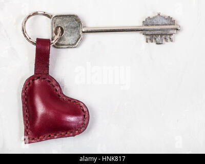 big key with red leather heart shape keychain on concrete board Stock Photo