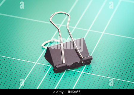 black binder clips isolated on cutting mat Stock Photo