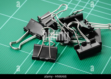black binder clips isolated on cutting mat Stock Photo