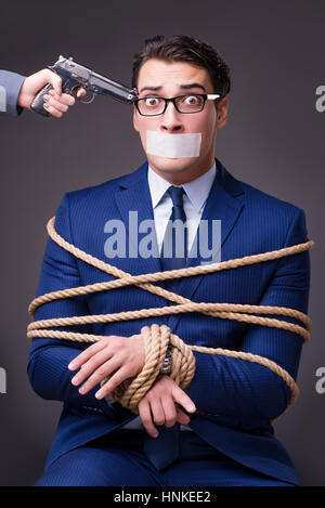Businessman taken hostage and tied up with rope Stock Photo