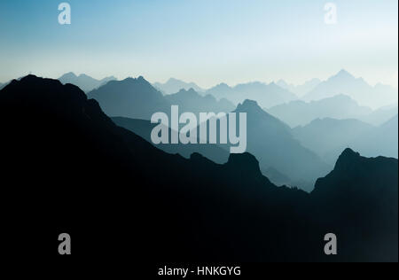 Spectacular blue and cyan mountain ranges silhouettes. Summit crosses visible. Stock Photo