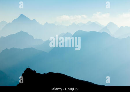 Spectacular blue and cyan mountain ranges silhouettes. Summit crosses visible. Stock Photo