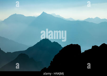 Spectacular blue and cyan mountain ranges silhouettes. Summit crosses visible. Stock Photo