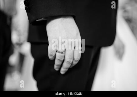 Close up hand of groom with wedding ring at church ceremony. Black and white photo Stock Photo