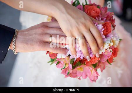 bride and groom hand with rings on wedding bouquet Stock Photo