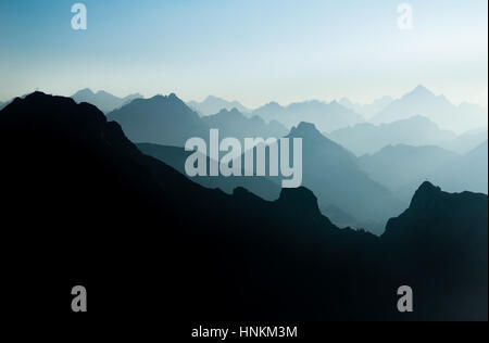 Spectacular blue and cyan mountain ranges silhouettes. Summit crosses visible. Stock Photo