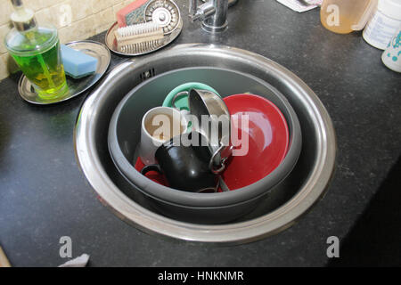 dirty dishes piling up in a round sink Stock Photo