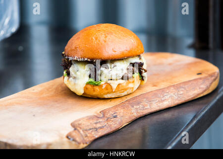 Burger with melted cheese in a bun. Stock Photo