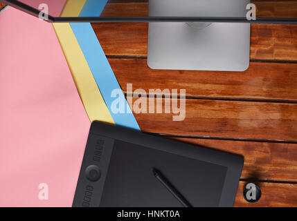 Wooden designer table view from top with graphic tablet and colorful paper Stock Photo