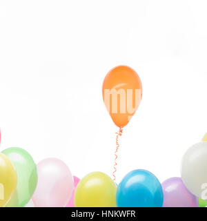 concept image of a orange balloon rising from his colorful group, white background Stock Photo