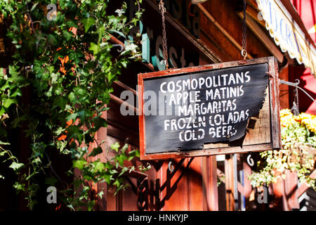 A weather worn sign above a bar doorway in Greenwich Village, New York, advertising cold refreshing drinks for sale Stock Photo