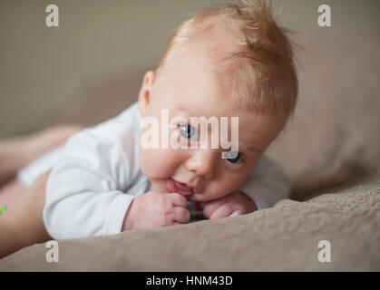 little boy in a white shirt on the bed Stock Photo