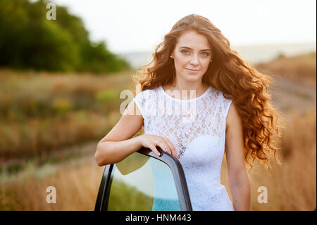 beautiful bride near the car at a wedding a walk in the field Stock Photo