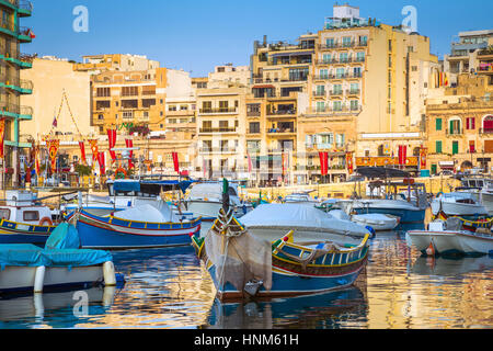 St.Julian's, Malta - Traditional Luzzu fishing boats at Spinola bay at sunrise Stock Photo
