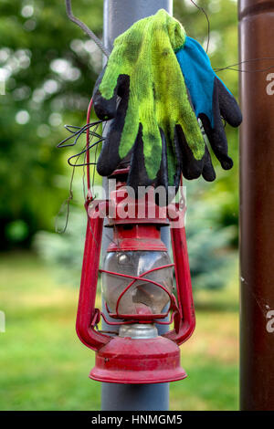 Working gloves and oil lamp hanging from pole. Stock Photo