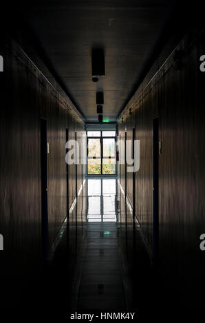 Dark corridor in apartment building with bright window at the end. Stock Photo