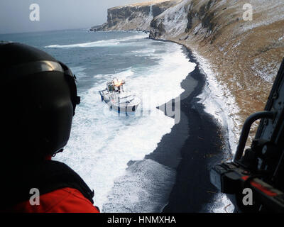Alaska, USA. 13th Feb, 2017. A U.S. Coast Guard MH-60 Jayhawk helicopter crew surveys the area around the fishing vessel Predator prior to hoisting three people off sinking ship February 13, 2017 in Cold Bay, Alaska, near , Feb. 13, 2017. The ship ran hard aground, causing it to take on water through an eight inch crack on the hull.   (USCG via Planetpix) Credit: Planetpix/Alamy Live News Stock Photo