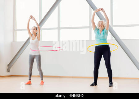 Positive active women rotating hula hoops Stock Photo