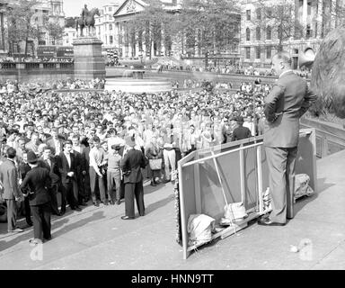 An orange thrown from the crowd lies on the plinth of Nelson's Column behind Sir Oswald Mosley, leader of the Union Movement, after hitting him in the far as he started to address a rally in Trafalgar Square, London. Sir Oswald's speech was accompanied by persistent jeering from the audience. Stock Photo