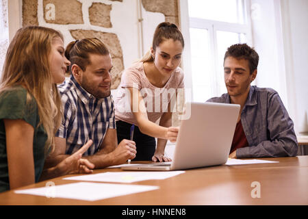 Professional male and female business team in an interesting meeting watching an interactive presentation looking and pointing at laptop pc on the des Stock Photo