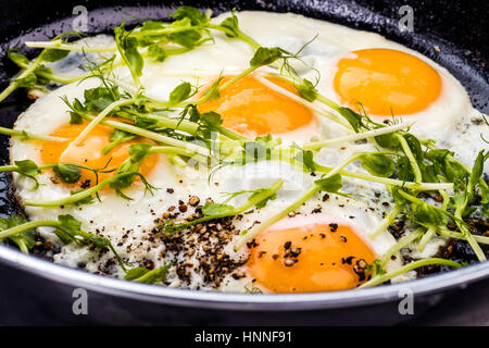 backed eggs sunny side up with fresh Peas sprouting Stock Photo