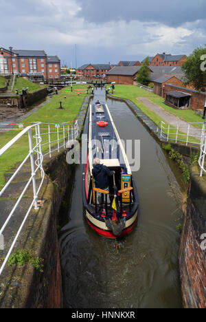 Narrowboat exiting the locks on the Shropshire Union Canal in Ellesmere Port where the inland waterway network connects to the Manchester Ship Canal Stock Photo