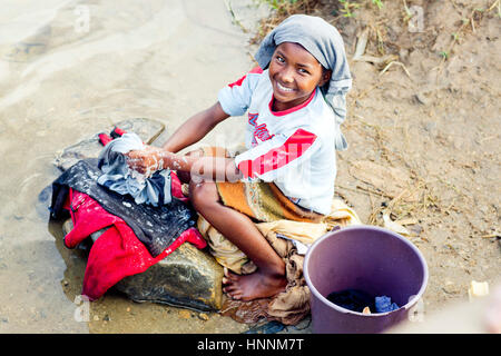 Young malagasy girl washing clothes in the river in Madagascar Stock Photo