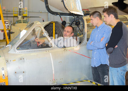 mechanic showing young men inside of cockpit Stock Photo