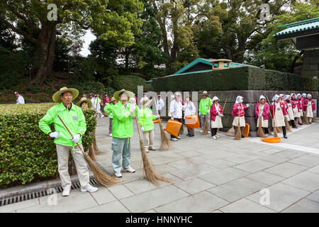 TOKYO, JAPAN - CIRCA APR, 2013: Cleaning workers with brooms in red and green clothes are on the inner area of Tokyo Imperial Palace, on the Kyuden To Stock Photo
