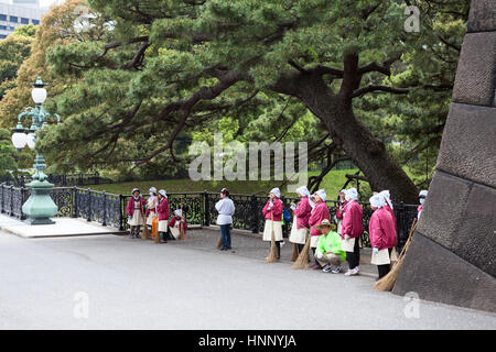 TOKYO, JAPAN - CIRCA APR, 2013: Woman janitors with brooms in pink clothes are on the inner area of Tokyo Imperial Palace, on the Kyuden Totei Plaza n Stock Photo