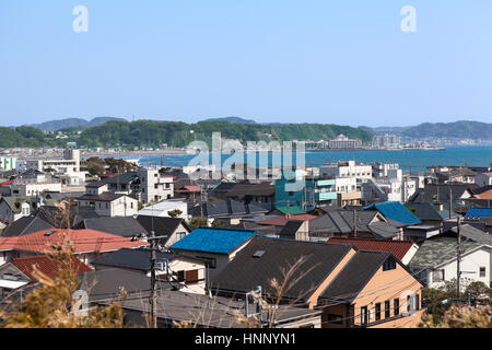 KAMAKURA, JAPAN - CIRCA APR, 2013: Top view at the Kamakura town. Houses with color roofs are on the coastline of Pasific ocean. Kamakura is a small t Stock Photo