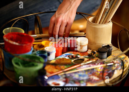 Artist painting easel studio. Cropped shot hands paints with brush. Stock Photo