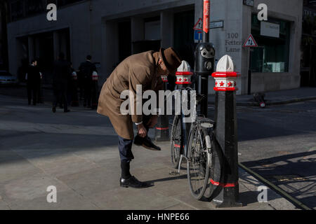 A cyclist tucks trousers into socks before riding away down Fetter Lane, on 13th February 2017, in the City of London, United Kingdom. Stock Photo