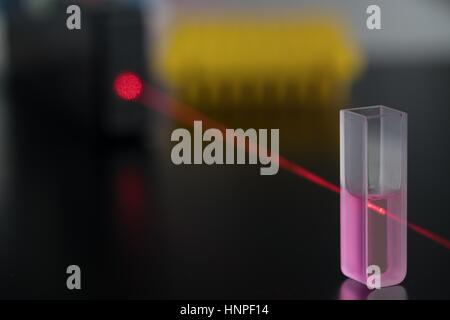 Quartz cuvette for laser chromatography with red liquid. Physical chemistry laboratory Stock Photo