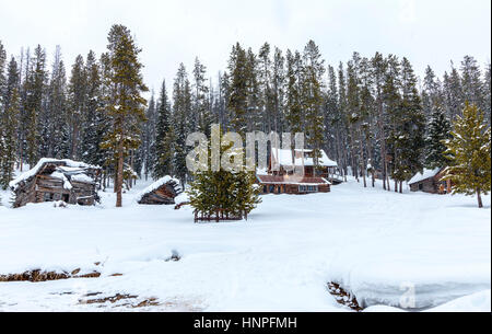 Rustic buildings sit among the trees at Burgdorf Hot Springs  near McCall, ID. Light snowfall softens the landscape. Stock Photo