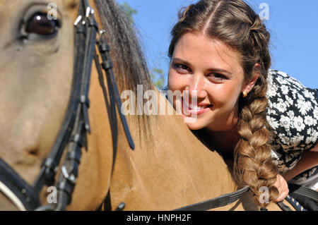 young attractive woman horseback riding in sunny day, looking at camera ...