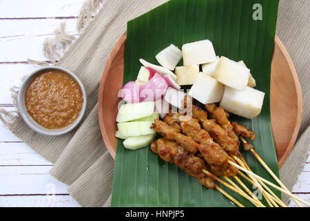 Chicken satay. Popular grilled food in Singapore and Malaysia, served with peanut sauce, rice cake, cucumber, and shallot. Stock Photo