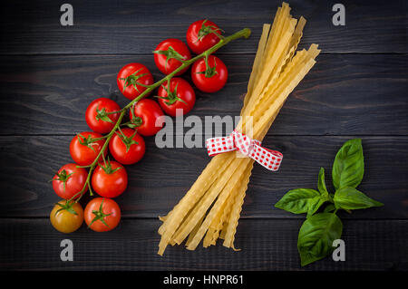 Spaghetti and tomatoes with herbs on an old and vintage wooden background Stock Photo