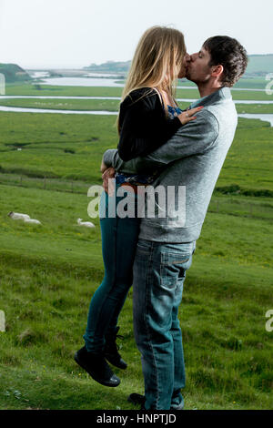 A couple recently engaged show their love for each other near seven sisters, East Sussex, UK. Stock Photo