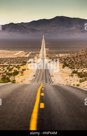Classic vertical view of an endless straight road running through the barren scenery of famous Death Valley on a sunny day in summer, California, USA Stock Photo