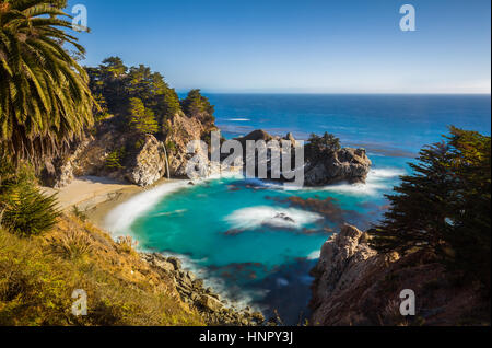 Classic postcard view of famous McWay Falls in golden evening light at sunset on a beautiful sunny day with blue sky in summer, Big Sur, California Stock Photo