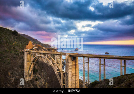 Scenic panoramic view of historic Bixby Creek Bridge along world famous Highway 1 in evening twilight with dramatic clouds, Big Sur, California, USA
