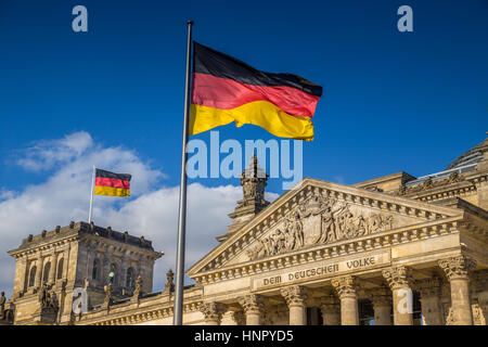 German flags waving in the wind at famous Reichstag building, seat of the German Parliament, on a sunny day with blue sky, Berlin Mitte, Germany Stock Photo